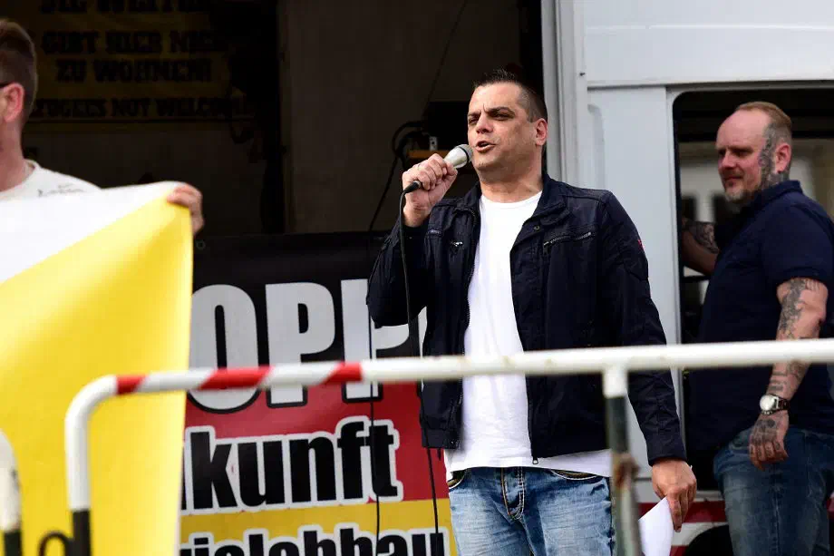 Auf das Verlesen der Veranstaltungsauflagen verzichteten die Veranstalter*innen weitestgehend. Stattdessen startete die Kundgebung gleich zu Beginn mit wüsten verbale Angriffen gegen Vertreter*innen der Stadt und Gegendemonstrant*innen. Auch die Sicherheitsbehörden schienen sich an der Nichterwähnung der Auflagen nicht zu stören. Ein polizeilicher Hinweis erfolgte zumindest nicht.