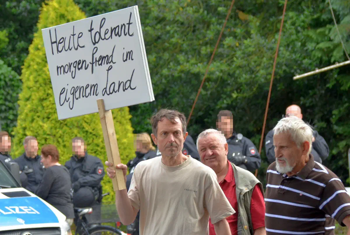 Gerhard Vierfuß trägt ein Schild mit einer Parole aus der Neonaziszene. Unter anderem verwendete die NPD Hamburg diesen Spruch auf einem ihrer Plakate.