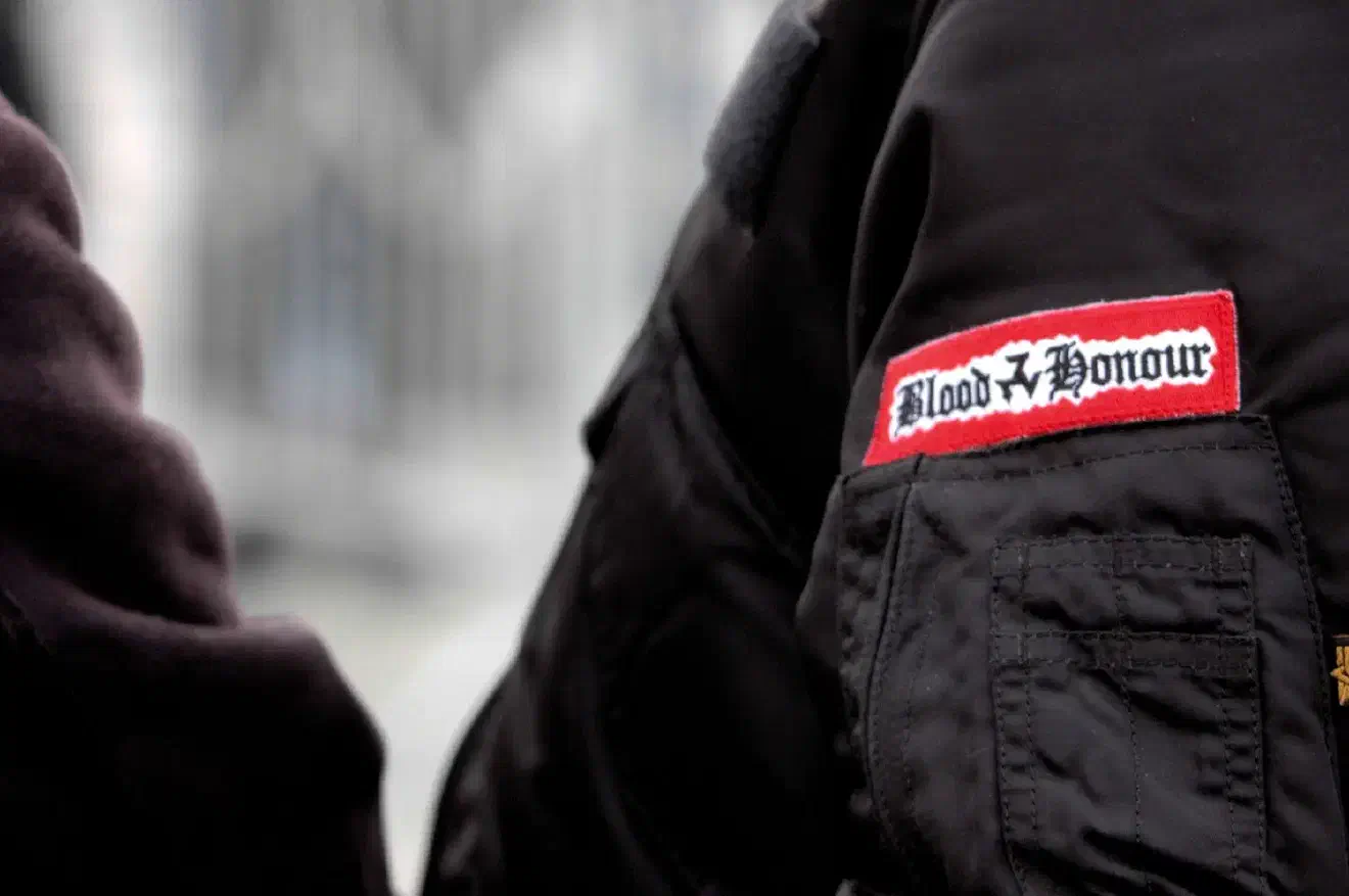 Bei "Blood & Honour" handelt es sich um ein internationales Netzwerk von Neonazis welche neonazistische Bands, deren Produzenten und militante Anhänger*innen miteinander koordiniert und das Ziel verfolgt nationalsozialistische Ideologie zu verbreiten. 