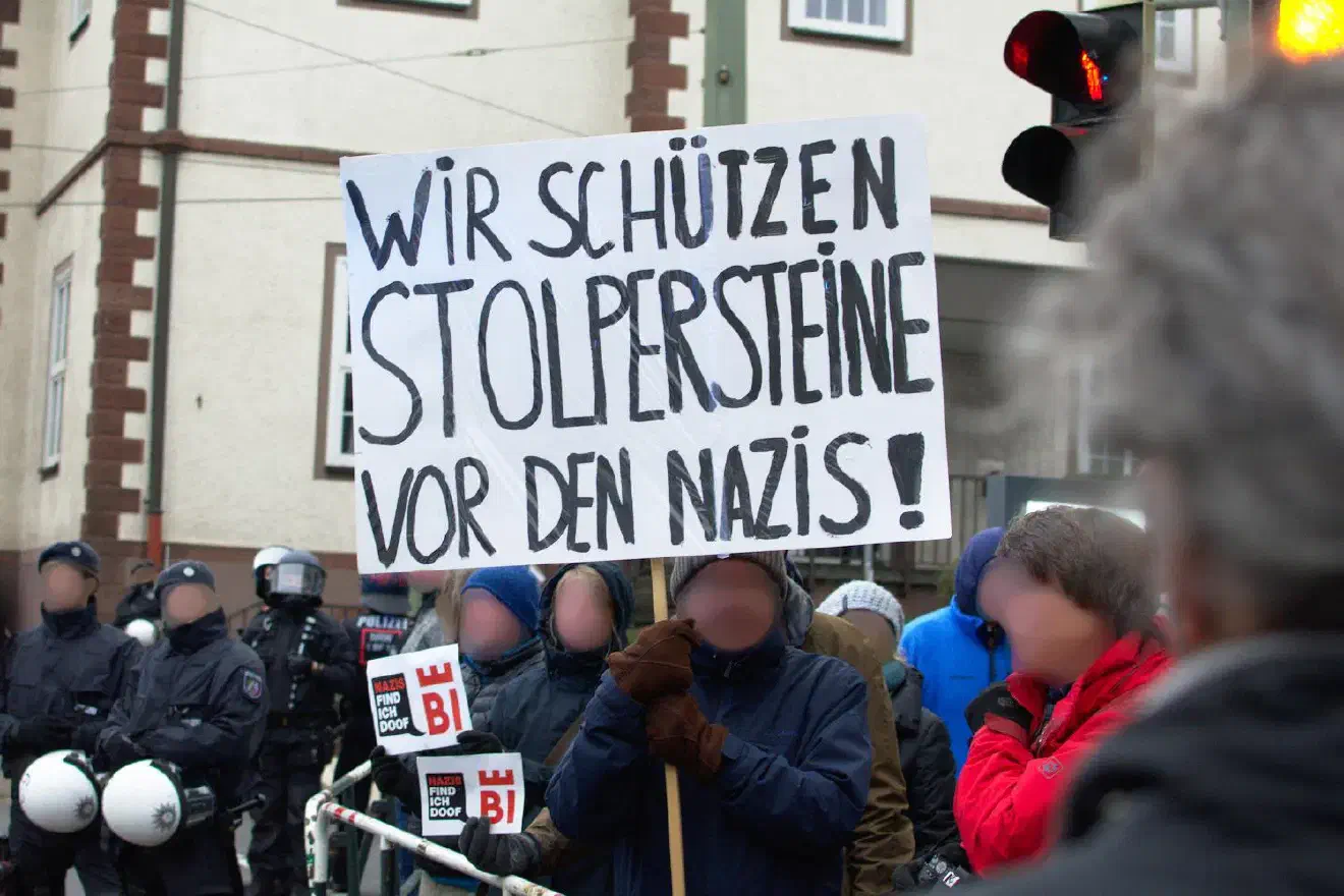 Über die gesamte Aufmarschstrecke gab es vielfältige antifaschistische Proteste. Hier stellten sich Menschen schützend vor sogenannte „Stolpersteine“, die an von Nazis deportierte jüdische Menschen erinnern.