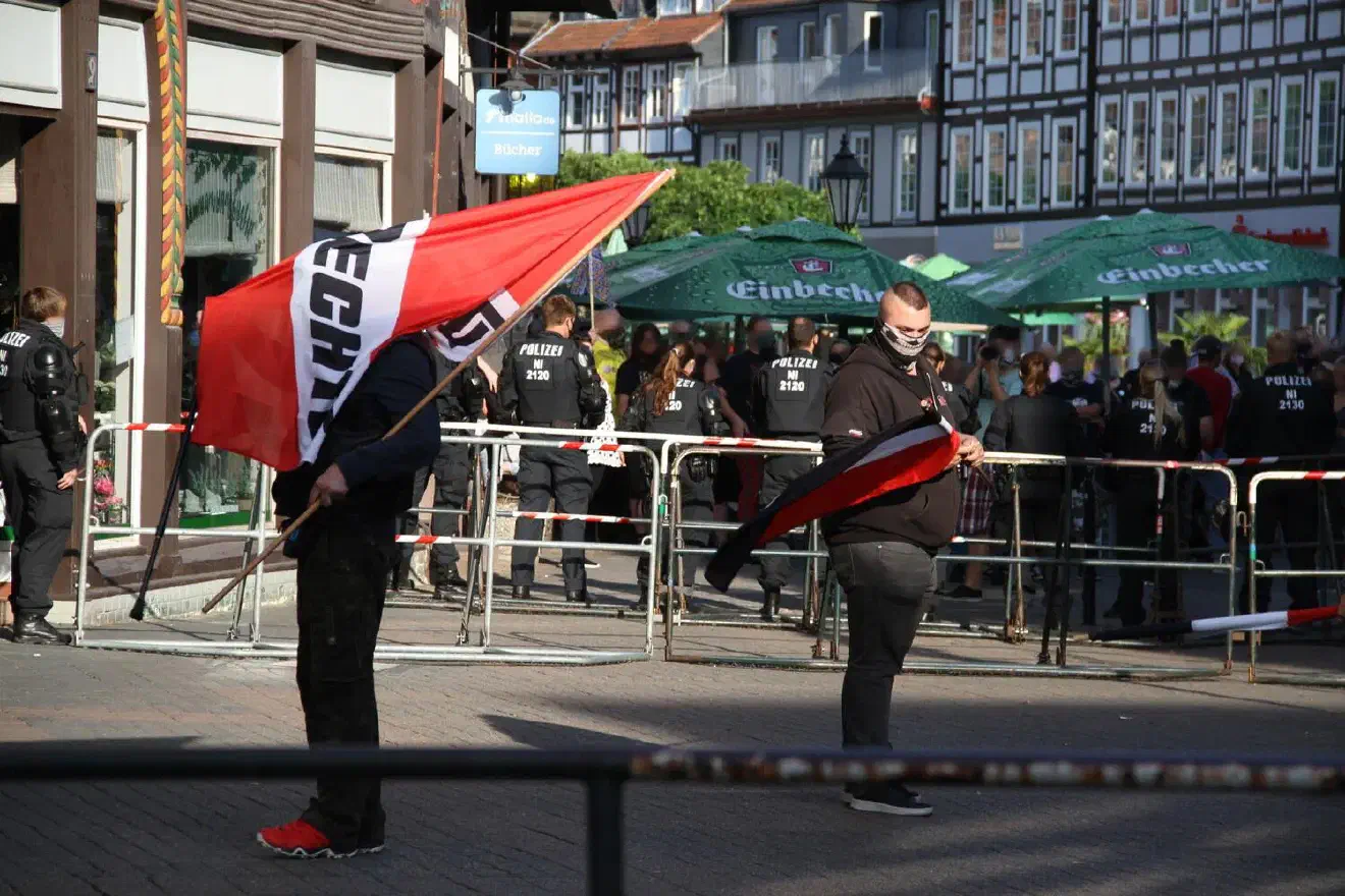 …, da sich auf der dem Marktplatz zu gewandten Seite der Kundgebung zahlreiche Menschen zu einer genehmigten Gegenkundgebung versammelt hatten und ihrerseits mit Musik und Reden aufwarteten,schien das nur begrenzt möglich zu werden.