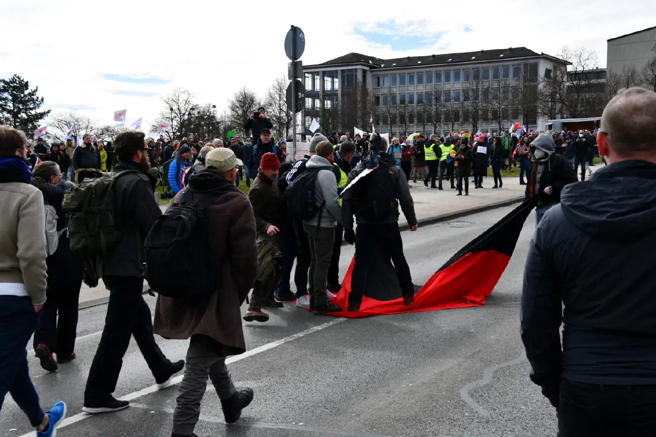 Als zwei Menschen mit einer schwarz-roten Fahne die Menge passierten, wurde es versucht, ihnen diese zu entwenden...