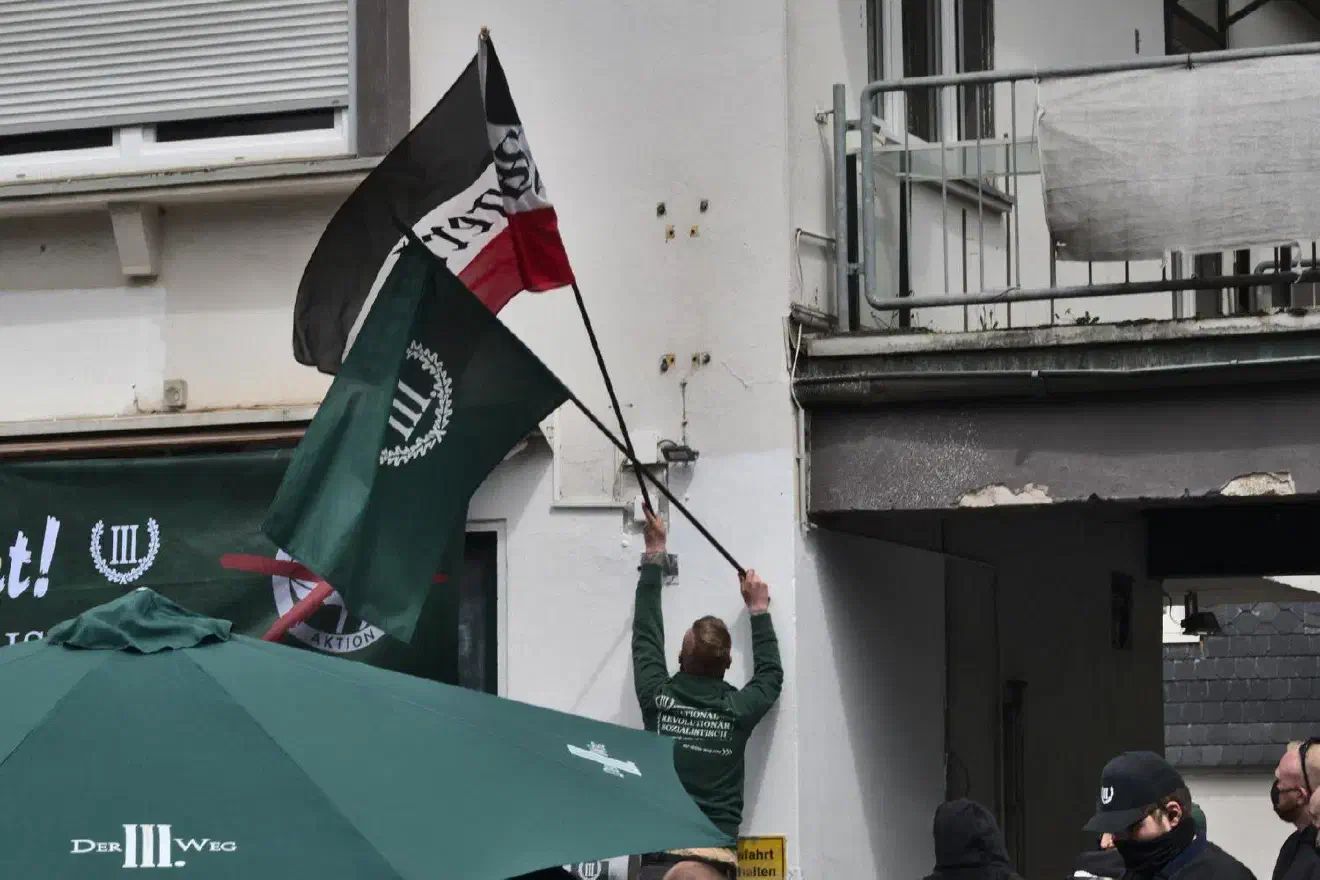 Julian Bender tauschte vor seinem letzten Redebeitrag, den er mit den Worten angekündigt hat, dass der achte Mai für sie kein Tag der Befreiung sei, eine Parteifahne durch eine schwarz-weiß-rote »Siegerland«-Flagge aus. ...