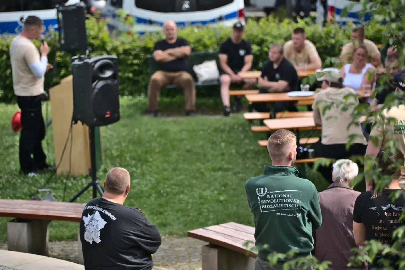 Auf dem kleinen Veranstaltungsgelände befanden sich neben einem Redner*innenpult ein Verpflegungsstand, ein Stand der Kampfsportgruppe »Körper & Geist«, ein Stand des Plauner Parteibüros P130, ein allgemeiner Partei-Infostand und ein Stand mit Traditionswaren. Vor dem Redner*innenpult waren Bierbänke und -tische aufgestellt.