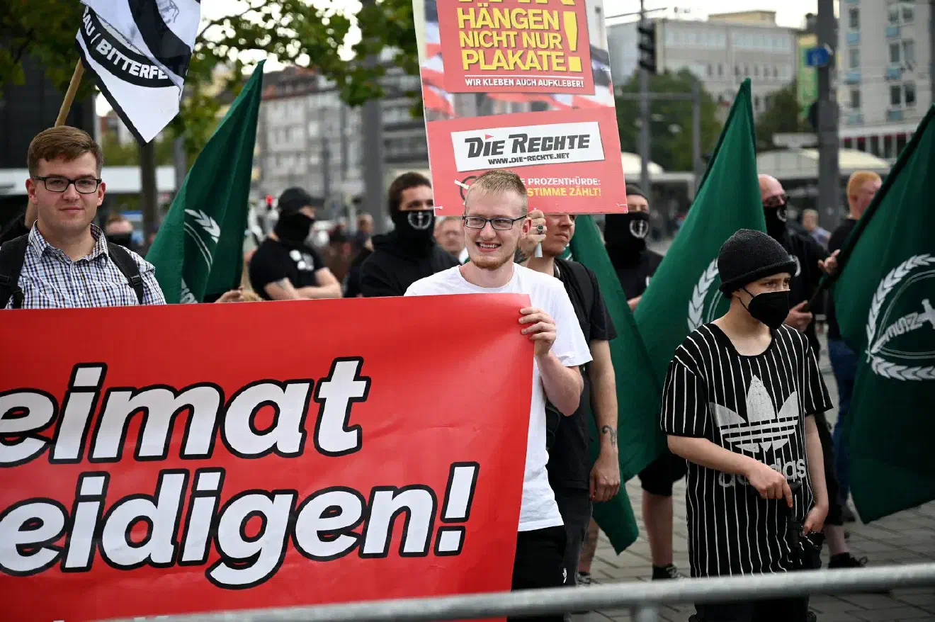 Sebastian Weigler (hier links im Bild), der längere Zeit nur noch als Einzelperson bei Demonstrationen in Braunschweig aufgetreten war, hatte dieses Mal drei junge Aktivisten dabei, sodass die JN die Möglichkeit hatte ihr mitgebrachtes Transparent ohne fremde Hilfe zu halten. Vom früheren Auftreten der JN Braunschweig und der JN Niedersachsen – sowohl was die Kleidung , aber auch die Disziplin betrifft-  war diese Gruppe weit entfernt, passte sich damit aber hervorragend dem Niveau der übrigen Teilnehmer*innen an. 