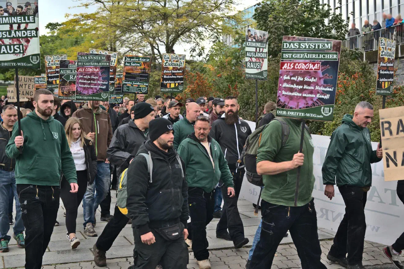 Yves Denk (ganz rechts mit Schild) ist normalerweise Trommler auf Veranstaltungen des III. Wegs. Dieses Mal wurden die Trommeln vor der Demonstration wieder eingepackt. Links im grünen Pullover des III. Wegs und mit Schild ist Maik Schmidt. Er war zuvor in der JN Brandenburg aktiv.
