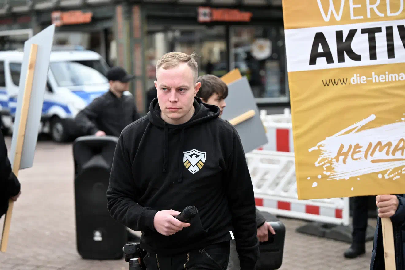 Ebenfalls vor Ort war mit Micha M. einer der wichtigsten Vertreter des völkischen Flügels des JN-Jugendverbands. M., der inzwischen auf eine jahrelange Sozialisation innerhalb der militanten Neonaziszene verweisen kann, gilt als ideologischer Hardliner. Die von ihm beeinflußten JN-Stützpunkte zeichnen sich durch umfangreiche Aktivitäten aus. Wanderungen, Kampfsport, völkische Feste sowie regelhafte Agitationen gegen politische Gegner*innen zählen hier zum Standart-Reportoire.
